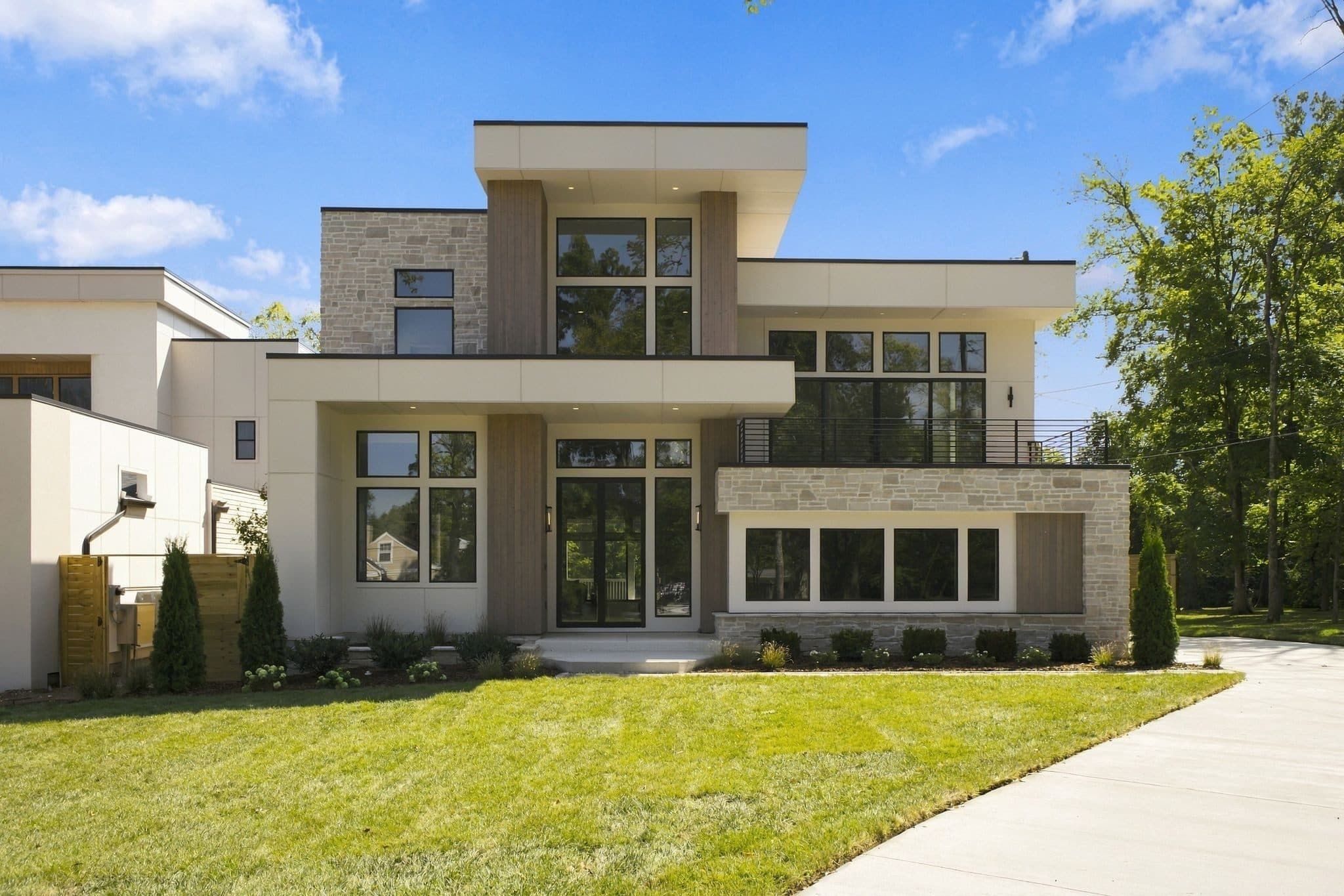 Front exterior of the new modern home with limestone and cedar accents and a wide front lawn at 4206B Belmont Park Terrace, one of the Green Hills homes for sale in Green Hills Nashville