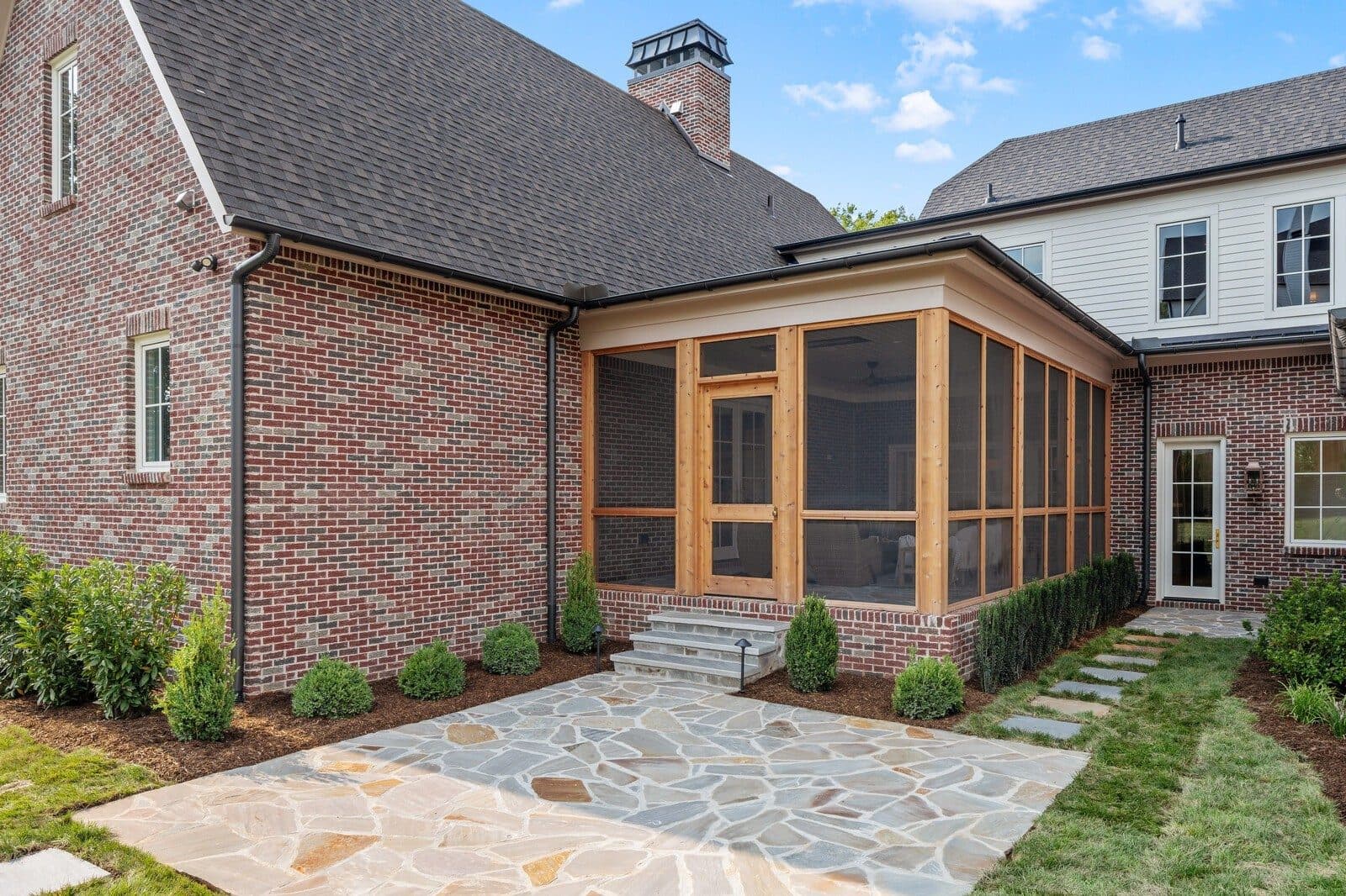 Rear of the brick home with the screened porch and a stone patio at 1113 Glenwood Ave, Green Hills Nashville