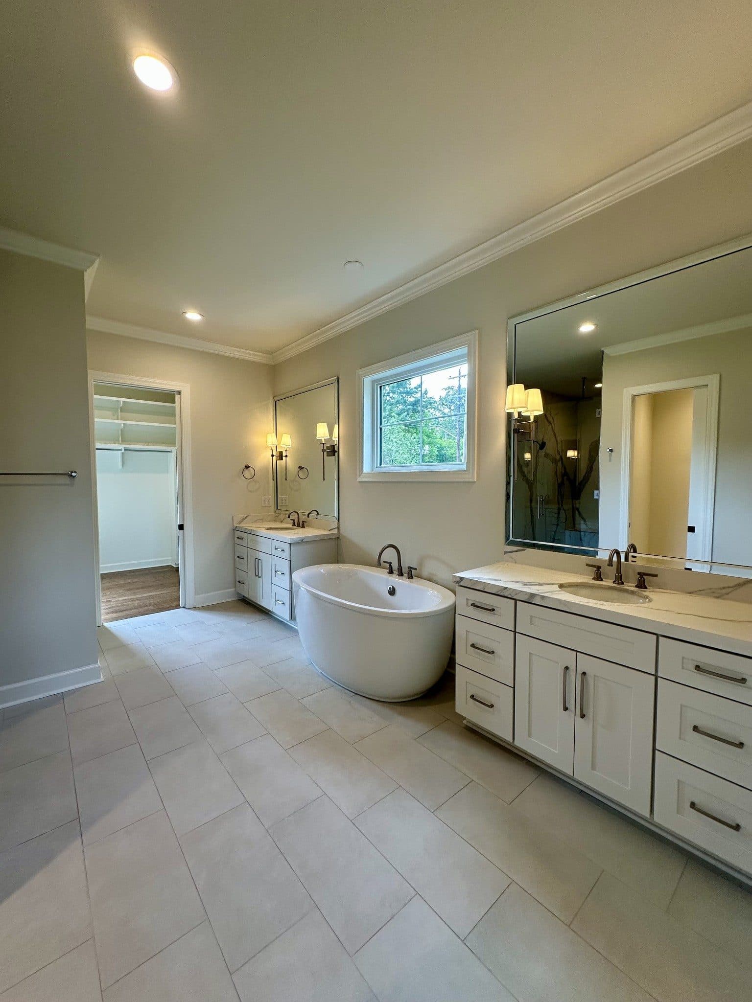 Primary bath with dual vanities, a freestanding soaking tub, and a walk in closet beyond at 3300 Trimble Road, Green Hills Nashville