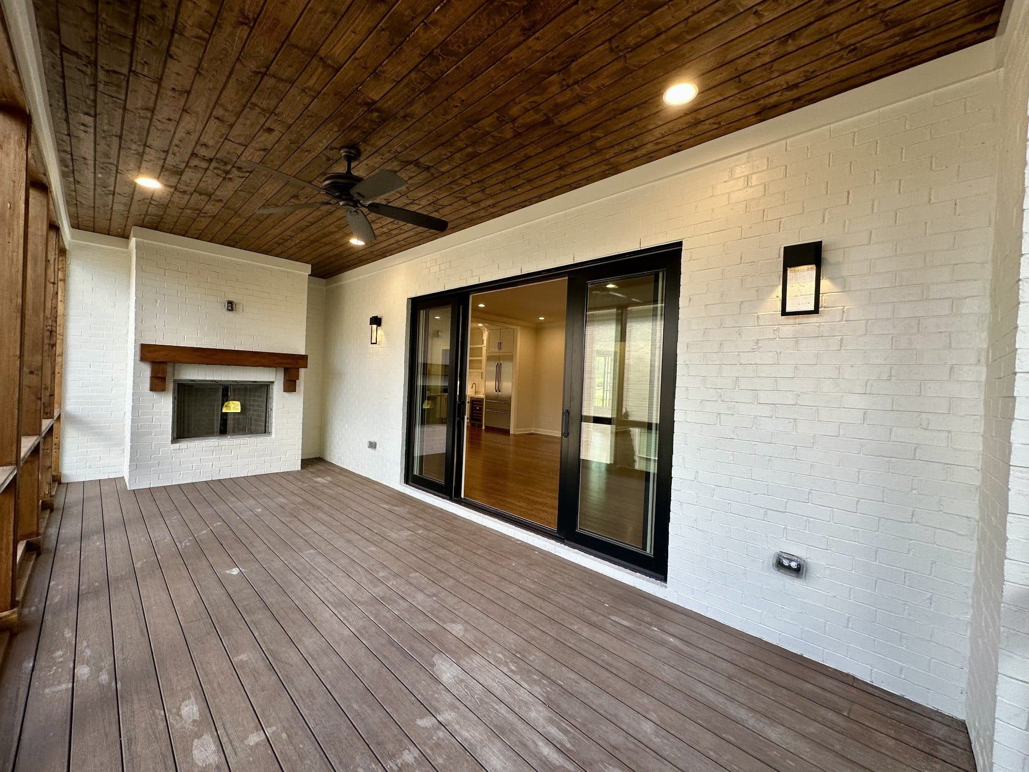 Covered rear porch with a wood plank ceiling, a white brick fireplace, and sliding glass doors at 3300 Trimble Road, Green Hills Nashville