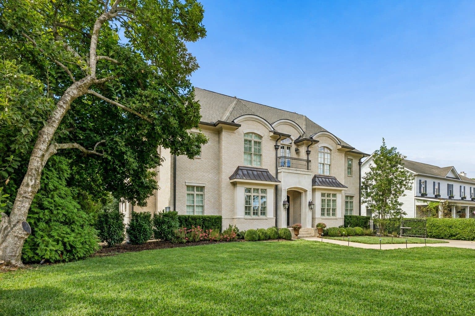 Angled front view of the light brick home with a mature tree and lawn at 4019 Vailwood Drive, Green Hills Nashville
