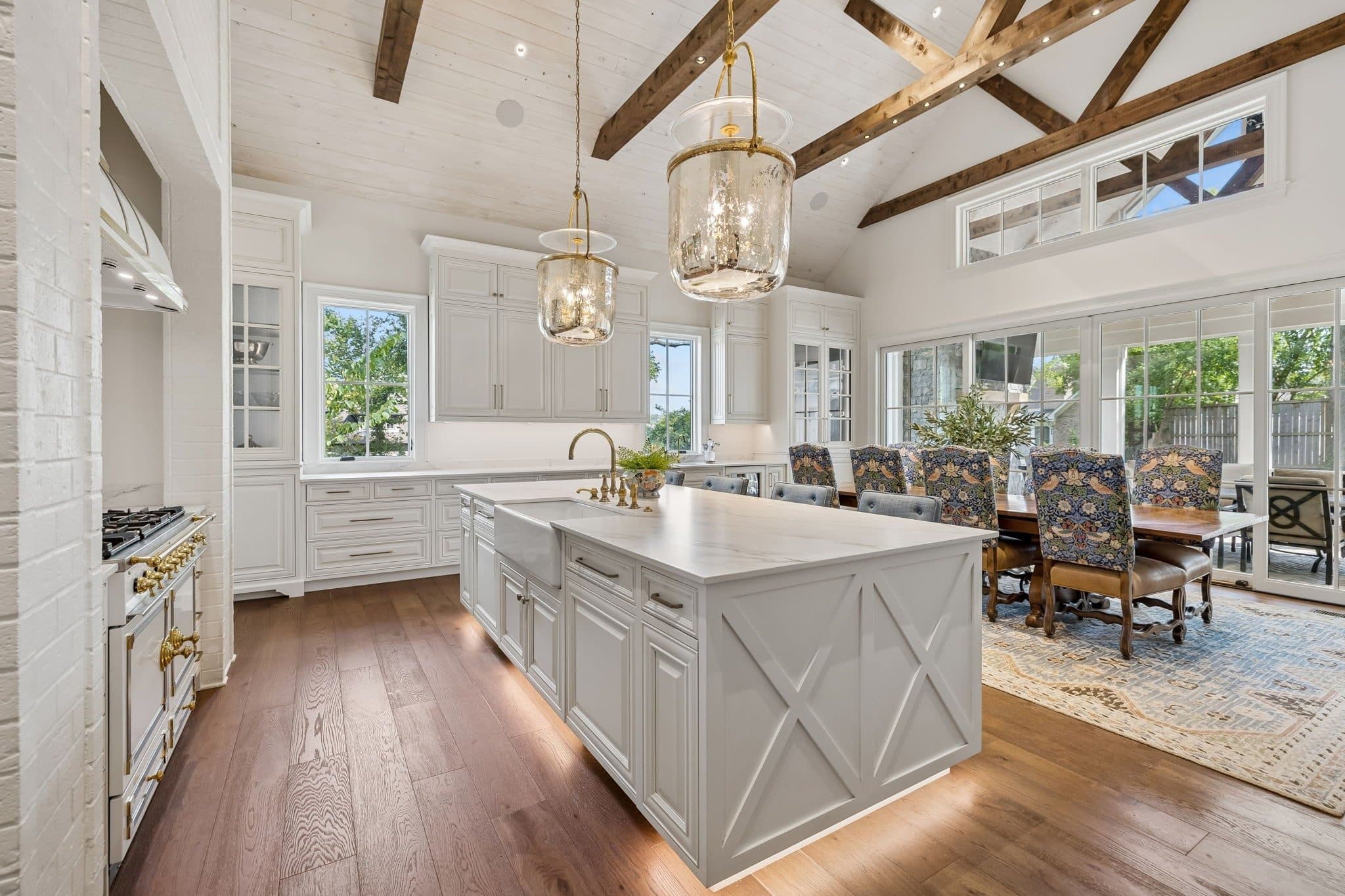 Kitchen with exposed wood beams, a large island, and a range set in white cabinetry at 2301 Warfield Lane, Green Hills Nashville