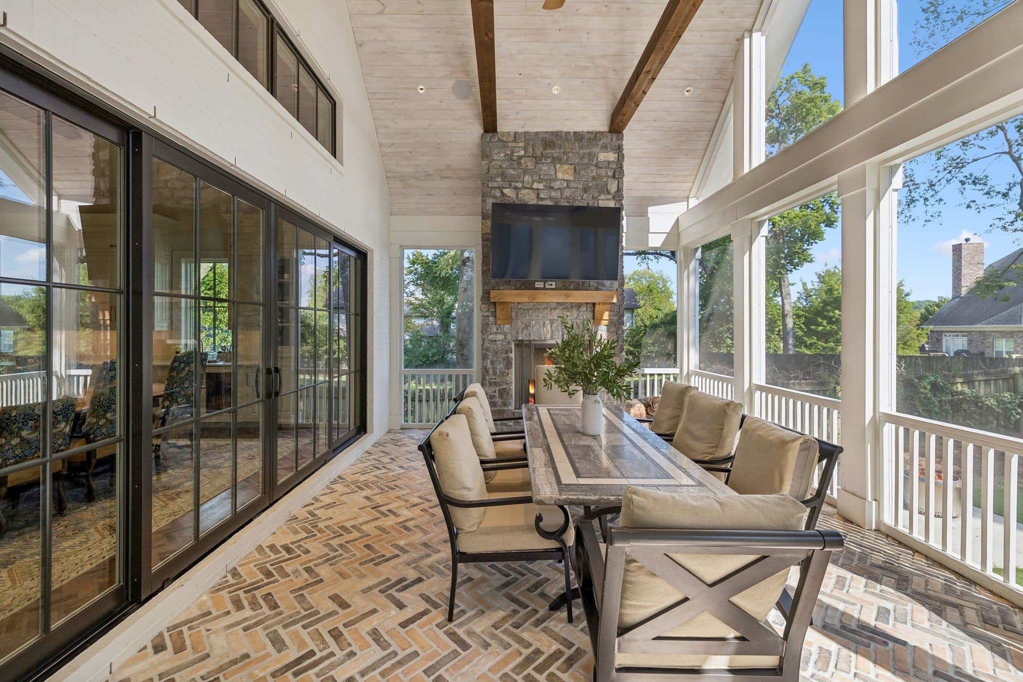 Screened porch with a stone fireplace, a dining table, and herringbone brick floors at 2301 Warfield Lane, Green Hills Nashville