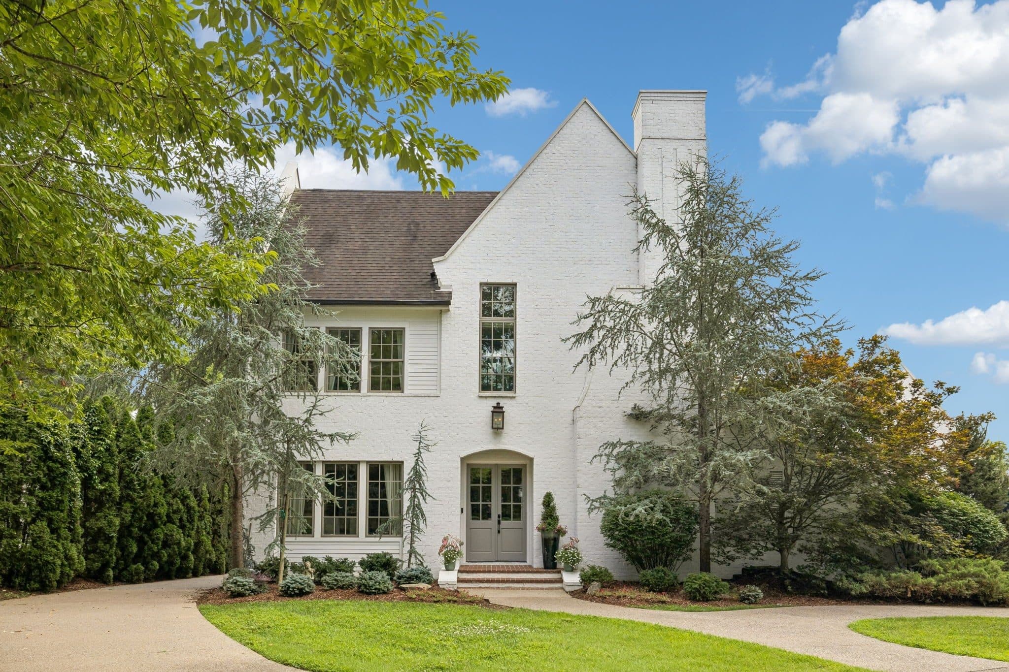 Front exterior of the white brick home with an arched entry and a curved driveway at 3719 Woodmont Boulevard, one of the Green Hills homes for sale in Green Hills Nashville